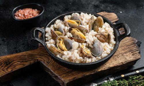 Seafood Risotto with clams in a skillet. Black backgroud. Top view